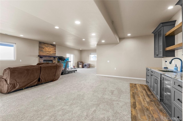 interior space with gray cabinetry, light stone countertops, sink, a fireplace, and wine cooler