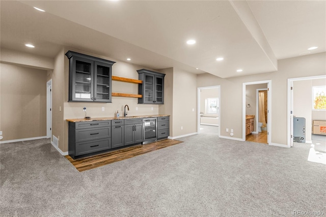 bar with beverage cooler, sink, dark carpet, and gray cabinets