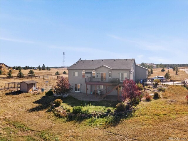 rear view of house featuring a rural view, a storage unit, and a lawn