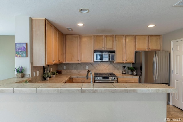 9760 Mayfair St Unit A, Englewood, CO 80112 - kitchen with stainless steel appliances, a peninsula, recessed lighting, tile countertops, and backsplash