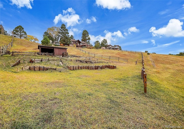 view of yard featuring a pole building, a rural view, an outdoor structure, and fence