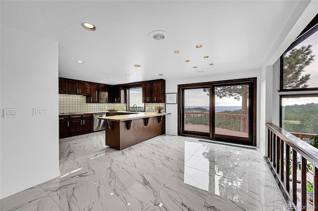 kitchen with marble finish floor, stainless steel dishwasher, a breakfast bar area, and backsplash