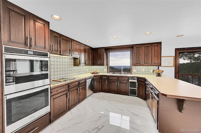 kitchen featuring tasteful backsplash, a peninsula, marble finish floor, stainless steel appliances, and light countertops