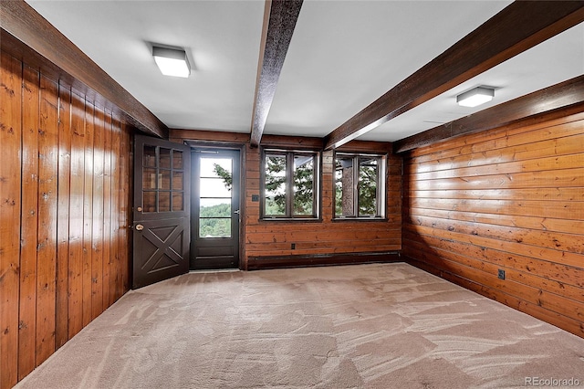 spare room with carpet, beam ceiling, and wooden walls