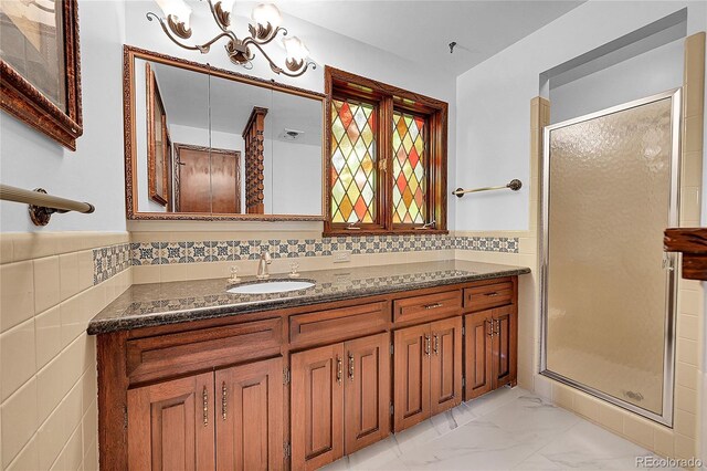 21849 Cabrini Blvd, Golden, CO 80401 - bathroom with vanity, a shower stall, marble look tile flooring, tile walls, and a wainscoted wall