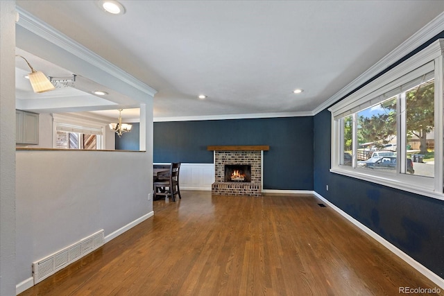 9350 Raleigh Ct, Westminster, CO 80031 - unfurnished living room featuring ornamental molding, a chandelier, healthy amount of natural light, wood finished floors, and a brick fireplace