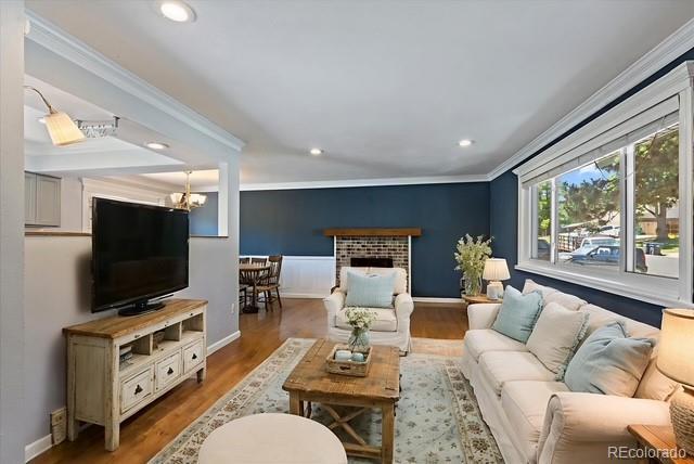 9350 Raleigh Ct, Westminster, CO 80031 - living room with ornamental molding, recessed lighting, wood finished floors, a chandelier, and a brick fireplace