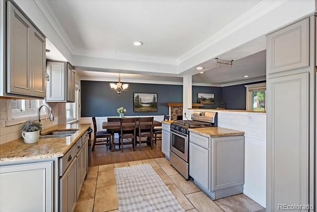 9350 Raleigh Ct, Westminster, CO 80031 - kitchen with stainless steel range with gas cooktop, backsplash, crown molding, a chandelier, and a raised ceiling