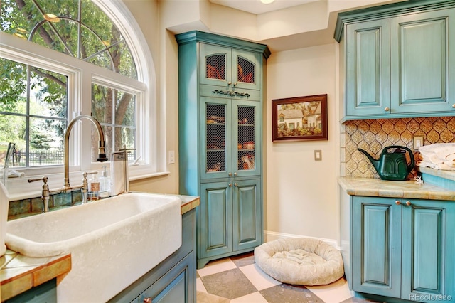 kitchen featuring decorative backsplash, light tile patterned floors, sink, and tile countertops