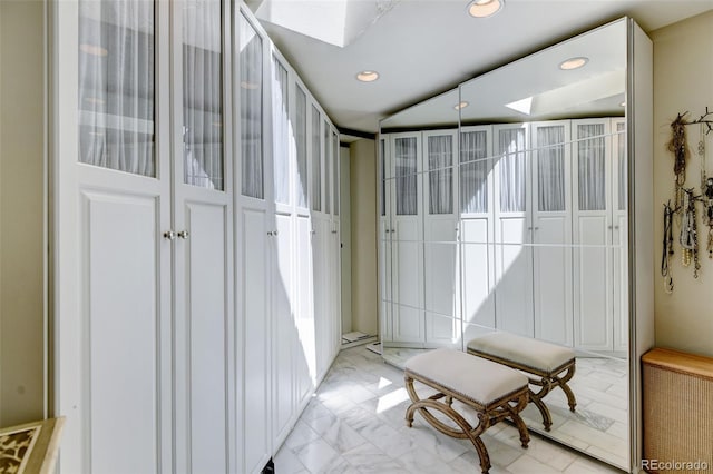 interior space with a skylight, marble finish floor, and recessed lighting