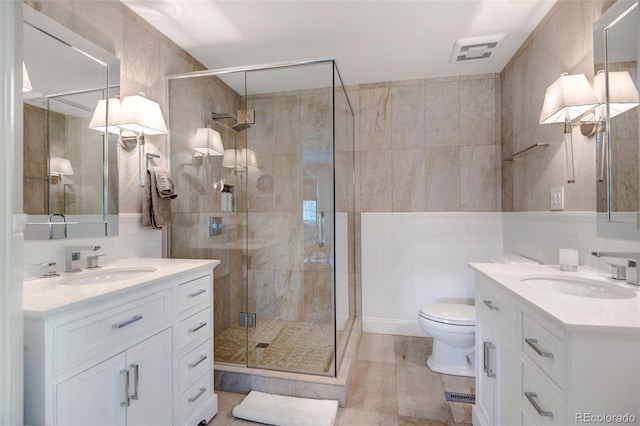 bathroom featuring a shower with shower door, toilet, tile patterned floors, tile walls, and vanity