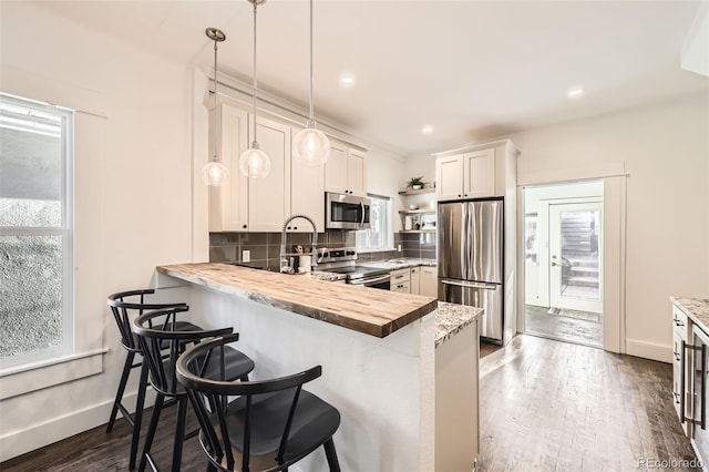 3521 Osage St, Denver, CO 80211 - kitchen featuring appliances with stainless steel finishes, a peninsula, pendant lighting, decorative backsplash, and a breakfast bar