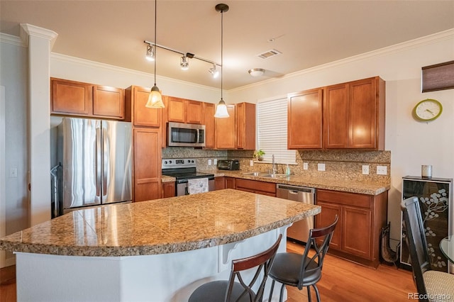 13456 Via Varra Unit 225, Broomfield, CO 80020 - kitchen with stainless steel appliances, light wood-style flooring, backsplash, ornamental molding, and a breakfast bar