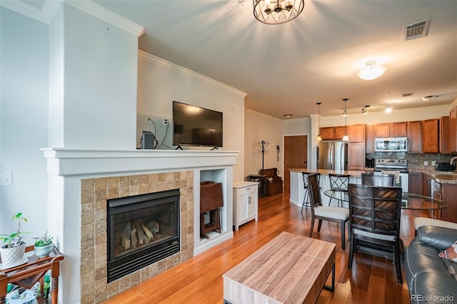 13456 Via Varra Unit 225, Broomfield, CO 80020 - living area featuring ornamental molding, a tile fireplace, and light wood-style flooring