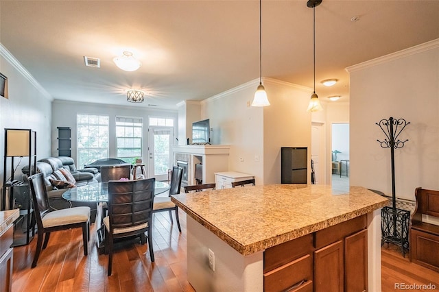 13456 Via Varra Unit 225, Broomfield, CO 80020 - kitchen with wood finished floors, crown molding, light countertops, decorative light fixtures, and open floor plan