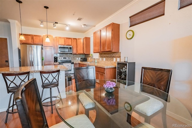 13456 Via Varra Unit 225, Broomfield, CO 80020 - kitchen featuring appliances with stainless steel finishes, a breakfast bar, backsplash, decorative light fixtures, and brown cabinets