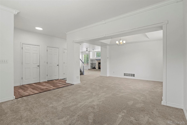 750 Capeglen Rd, Colorado Springs, CO 80906 - empty room with carpet, a chandelier, baseboards, a fireplace with raised hearth, and crown molding