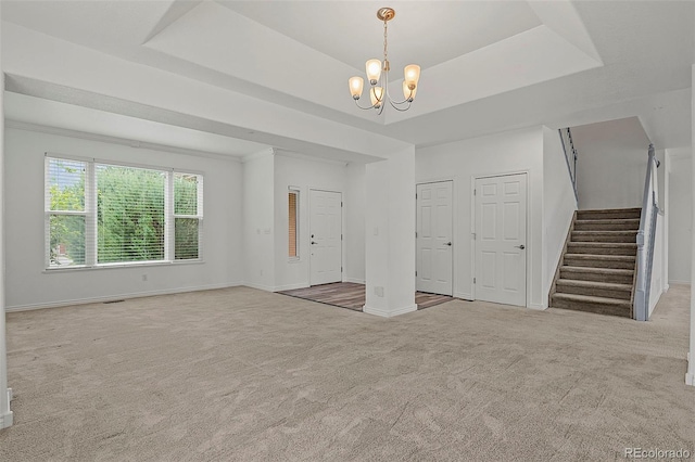 750 Capeglen Rd, Colorado Springs, CO 80906 - unfurnished living room with carpet floors, stairway, a chandelier, and a raised ceiling