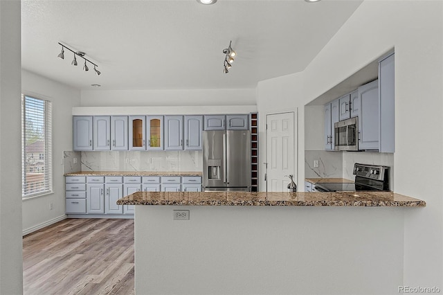 750 Capeglen Rd, Colorado Springs, CO 80906 - kitchen with appliances with stainless steel finishes, track lighting, a peninsula, stone countertops, and glass insert cabinets