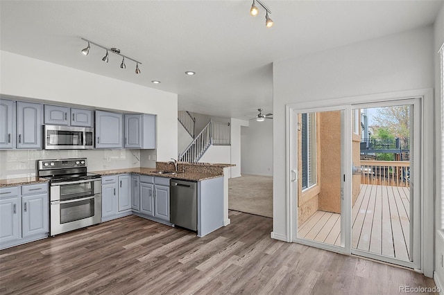 750 Capeglen Rd, Colorado Springs, CO 80906 - kitchen with stainless steel appliances, track lighting, gray cabinetry, a sink, and a peninsula