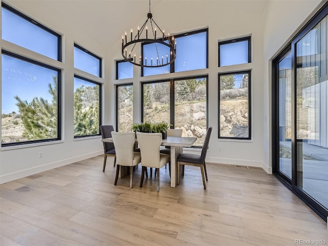 dining area featuring a chandelier, a towering ceiling, and light wood-type flooring