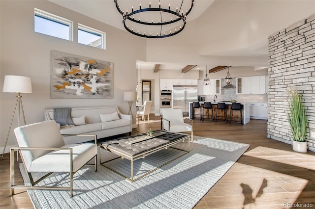 living room featuring light hardwood / wood-style flooring, a chandelier, and a high ceiling