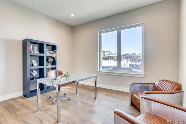 office space with light hardwood / wood-style floors and a healthy amount of sunlight