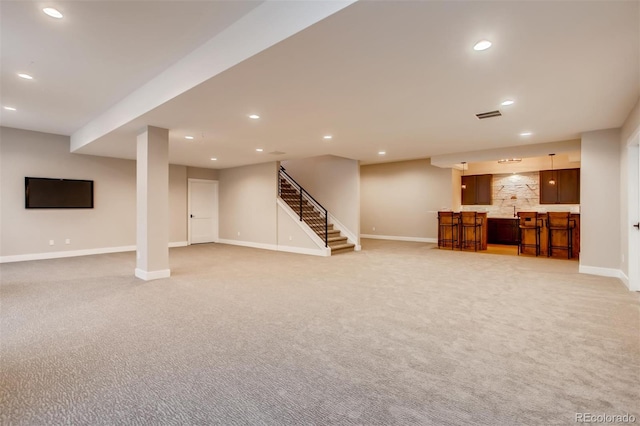 basement with light colored carpet and bar