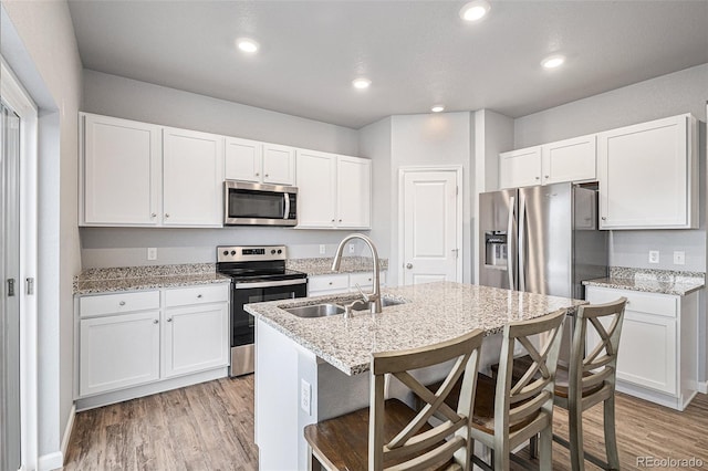 kitchen featuring a kitchen breakfast bar, white cabinets, appliances with stainless steel finishes, and sink