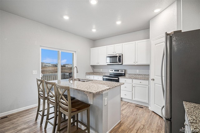 kitchen featuring a center island with sink, a breakfast bar, sink, white cabinetry, and stainless steel appliances