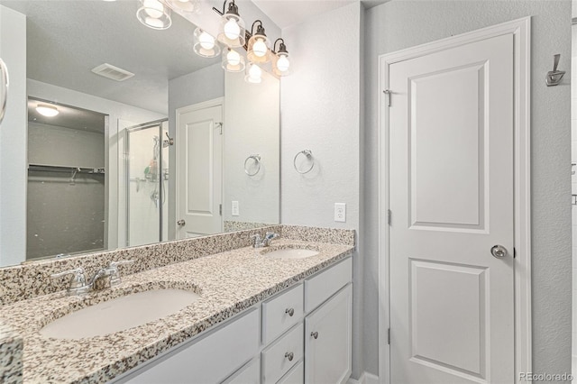 bathroom featuring a shower with shower door, a textured ceiling, and vanity