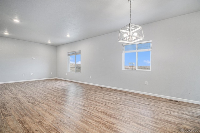 empty room featuring a chandelier and hardwood / wood-style flooring