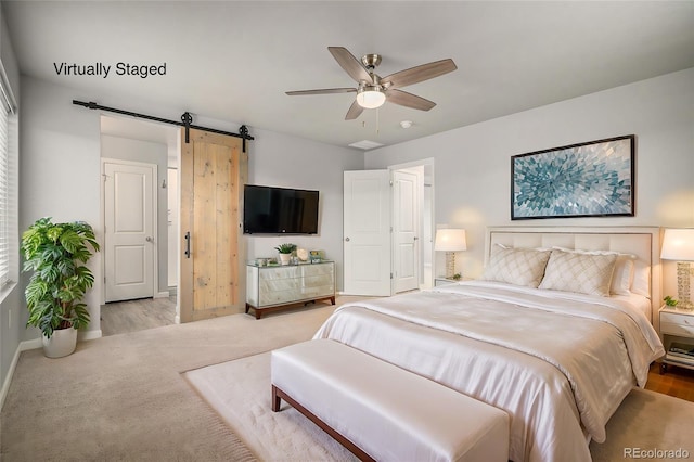 bedroom with ceiling fan, light carpet, and a barn door