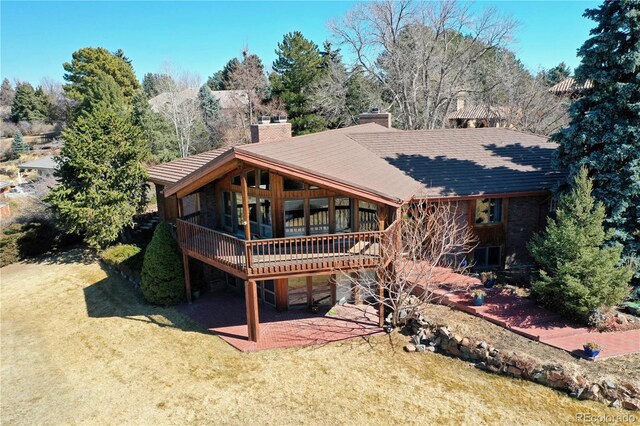 back of house with a patio area, a deck, a chimney, and a yard