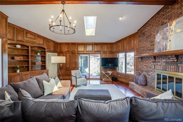 living room with lofted ceiling with skylight, a notable chandelier, wood finished floors, and wooden walls