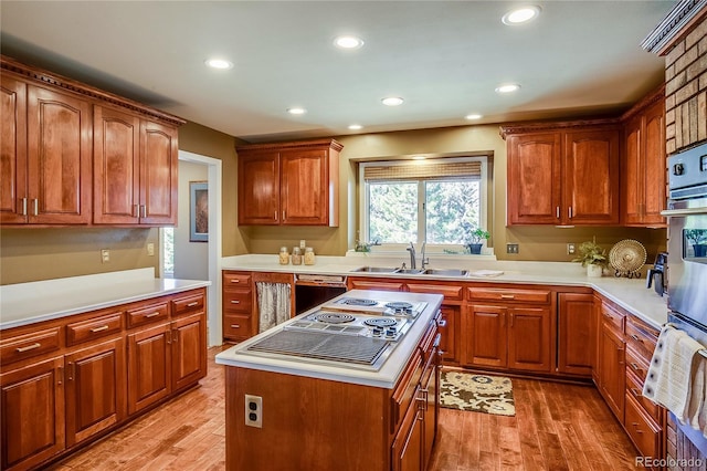 kitchen featuring dishwashing machine, stovetop with downdraft, light wood-style flooring, and a sink