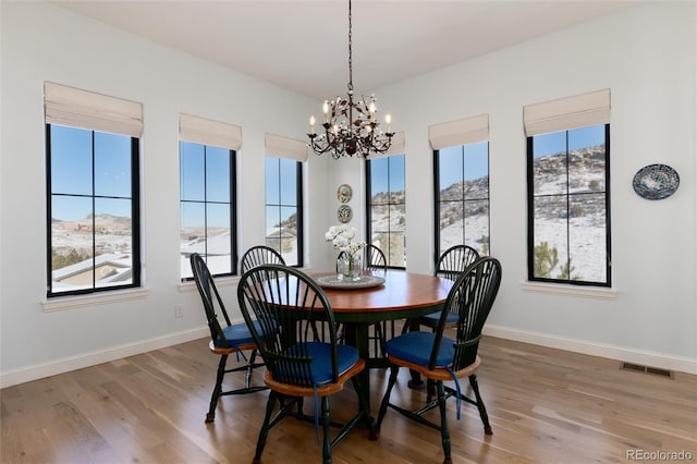 dining room with hardwood / wood-style floors, a notable chandelier, and a healthy amount of sunlight