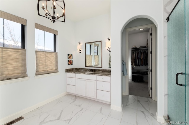 bathroom featuring a notable chandelier, vanity, and walk in shower