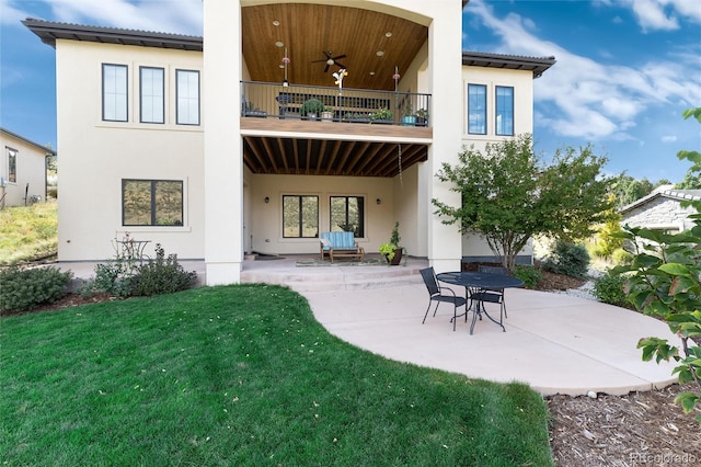 rear view of house featuring ceiling fan, a patio area, a balcony, and a yard