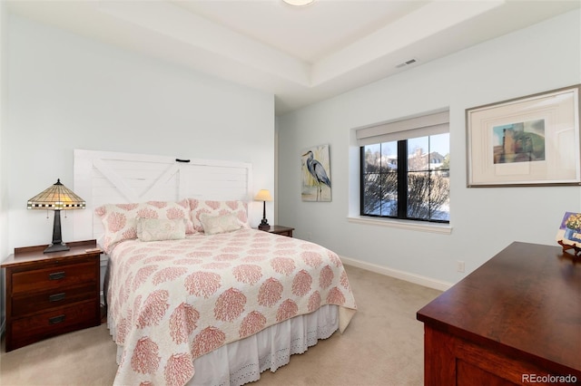 bedroom with light carpet and a raised ceiling