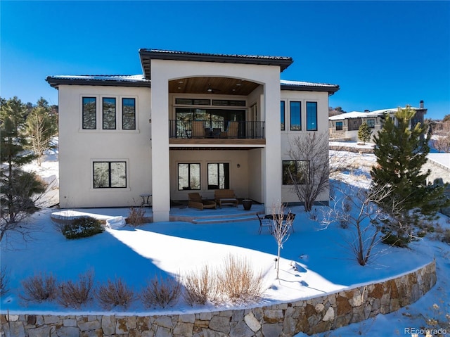 snow covered property featuring a balcony and an outdoor hangout area