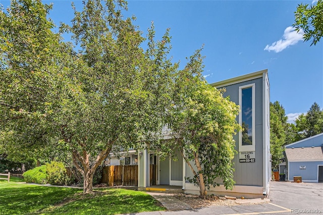 view of property hidden behind natural elements featuring a front yard