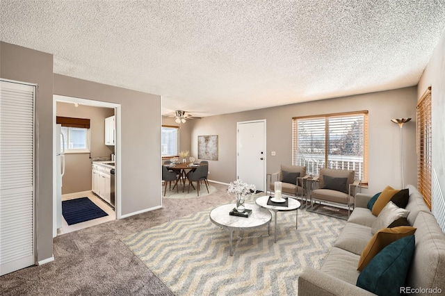 living room with a textured ceiling, light colored carpet, and ceiling fan