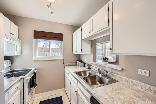 kitchen with white appliances, white cabinetry, plenty of natural light, and sink