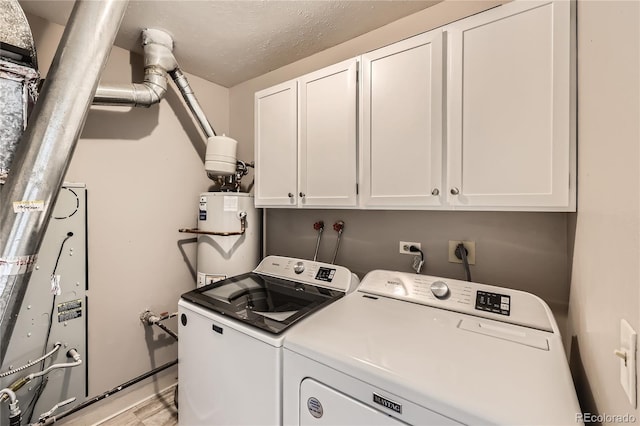 washroom with cabinets, gas water heater, light hardwood / wood-style flooring, a textured ceiling, and washing machine and clothes dryer