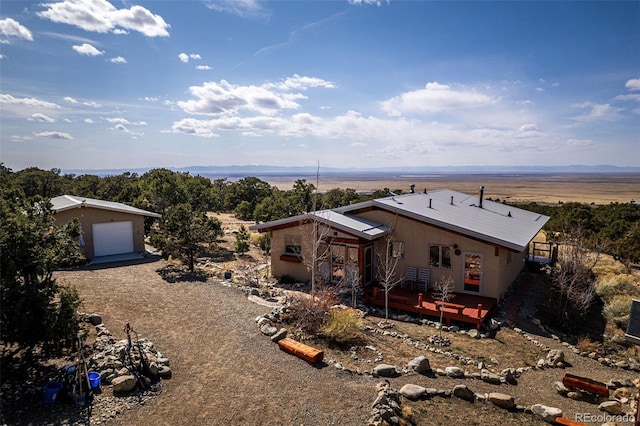 125 Deer Run, Mosca, CO 81146 - view of front facade featuring a wooden deck, a detached garage, stucco siding, and driveway