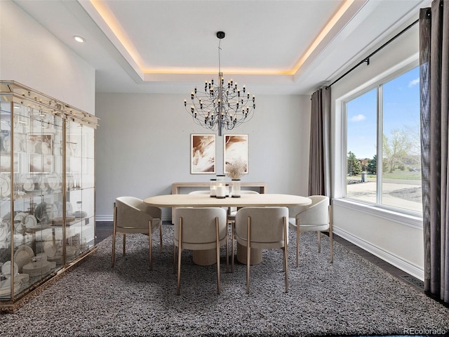 carpeted dining room with a notable chandelier and a raised ceiling