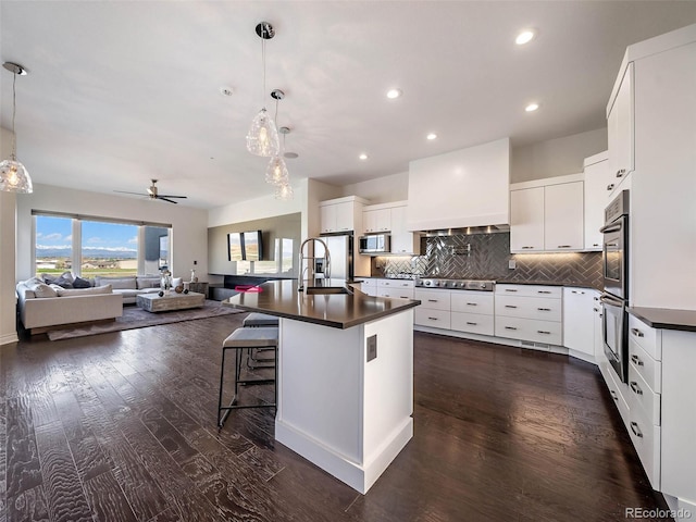 kitchen with appliances with stainless steel finishes, white cabinets, decorative light fixtures, and dark hardwood / wood-style floors