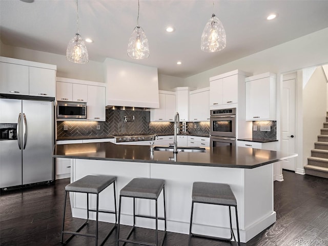 kitchen featuring sink, appliances with stainless steel finishes, a kitchen island with sink, and white cabinetry