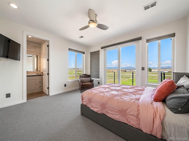 carpeted bedroom featuring a mountain view, connected bathroom, and ceiling fan